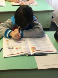 Gyermek az iskolapadban, előtte tankönyv