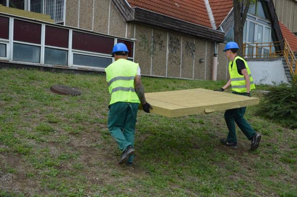 Két munkás viszi a szigetelőelemet