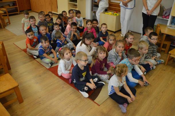 A gyerekek összegyűlve ülnek a szőnyegen