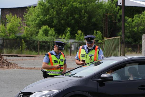 Az Ózdi Rendőrkapitányság két egyenruhása ellenőrzi egy fekete autó sofőrjét.