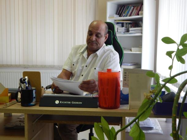 Dr. Sahin Fawaz címzetes főorvos ül az asztal mögött és papírokat néz át.