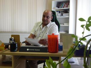 Dr. Sahin Fawaz címzetes főorvos ül az asztal mögött és papírokat néz át.