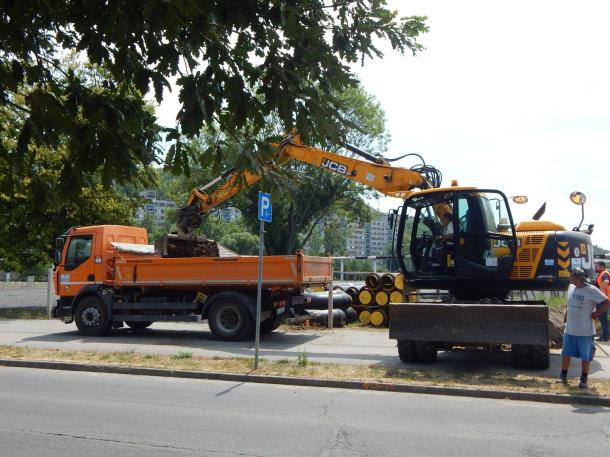 Egy markoló géppel pakolják a földet egy tehergépjármű platójára.