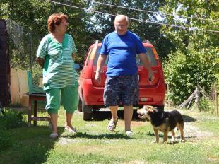 Tarr Mihály sétál párjával a kertben, kutyájuk társaságában.