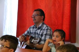 Csikai Sándor gitározik, a gyerekek énekelnek.