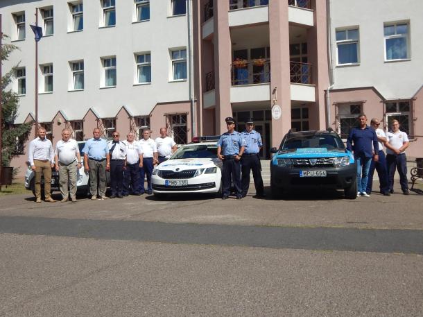 A rendészek, rendőrök, polgárőrök sorban állnak gépjárműveik mellett az Ózdi Rendőrkapitányság épülete előtt.