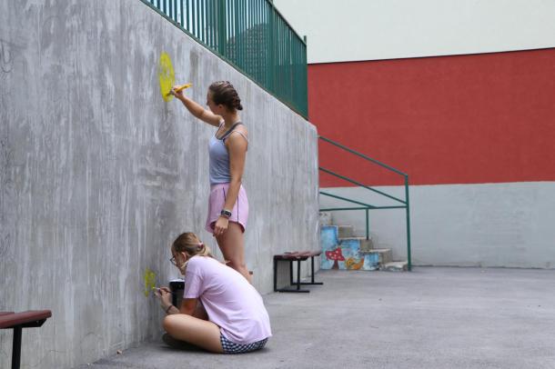 Két lány festi a támfalat.