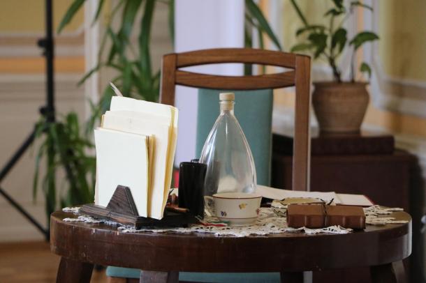 Közeli kép az asztal díszletéről – levélpapír, üveg, csésze és Júlia naplója.