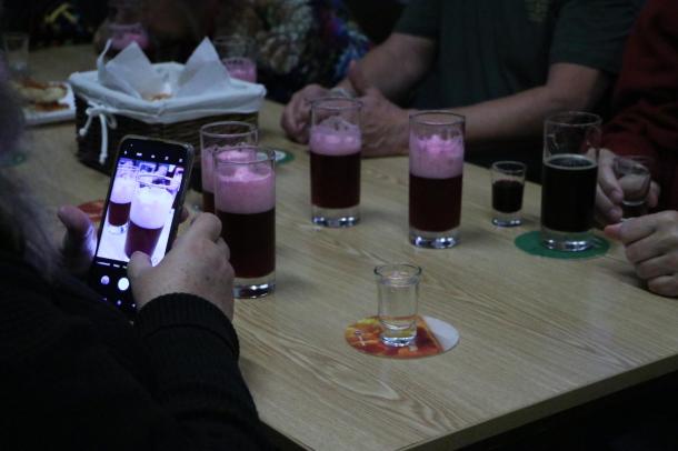 Sörös poharak az asztalon, az egyik ember telefonnal fényképezi őket.