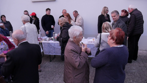 A közösség tagjai teáznak és sütit esznek a templom mellett.