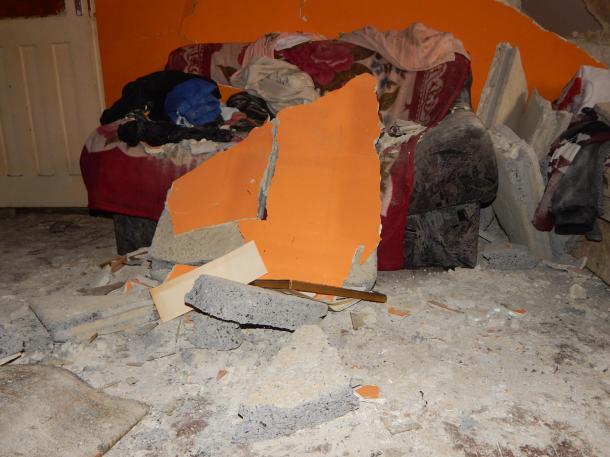 A robbanásban levált faldarabok a földön és a kanapén.