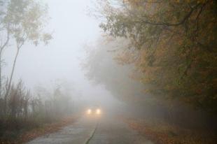 Ködös út, aminek a végén csak az autó lámpája látszik.