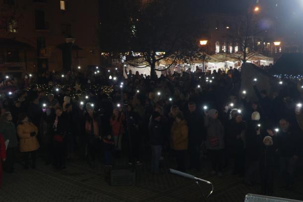 Távoli kép a tömegről, akik telefonjukkal világítanak.