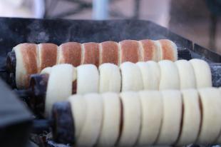 Közeli kép a kürtőskalácsokról sütés közben.