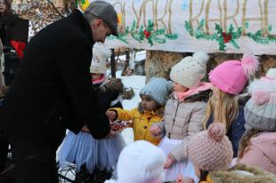Farkas Péter Barnabás területi képviselő szaloncukrot ad a műsorban résztvevő gyerekeknek.