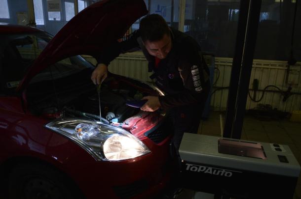 A szakember ellenőrzi a gépjármű világító- és fényjelző berendezéseit.