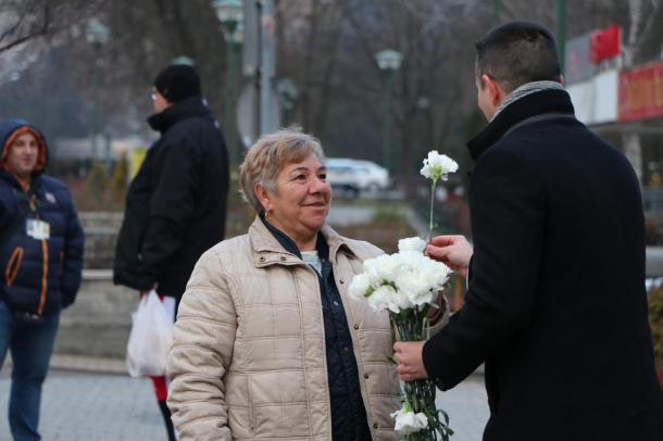 A polgármester virágot ad egy hölgynek nőnap alkalmából.