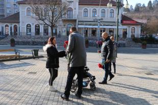 Kiss Sándor és Molnár Zsolt vörös szegfűvel köszönti a járókelő hölgyeket nőnap alkalmából.