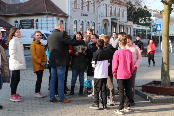 Angyal Béla virágot oszt az őt körülvevő lányoknak.