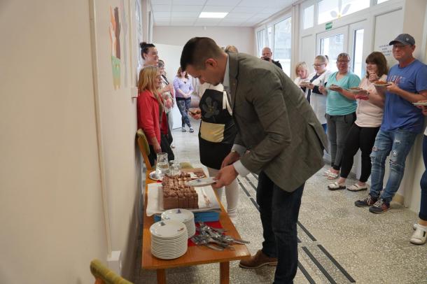Janiczak Dávid polgármester teszi a tányérokra a tortaszeletet.