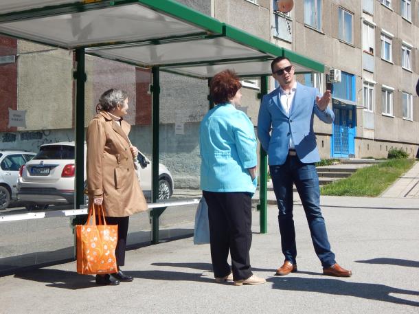 Városunk polgármestere beszélget a buszváróban várakozó hölggyel.