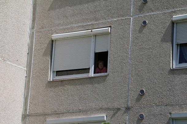 Egy idős hölgy az ablakból követi nyomon az eseményeket.