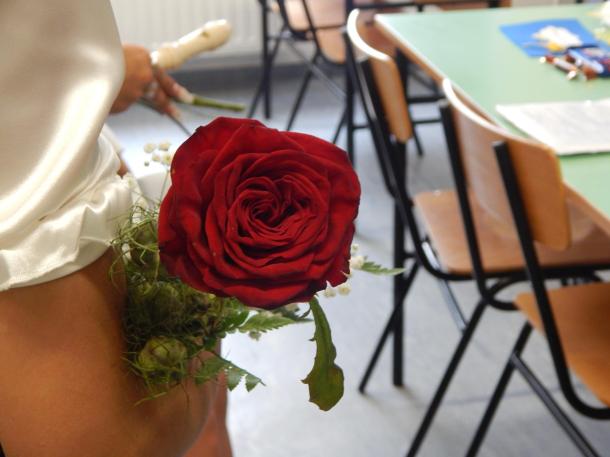 Egy ballagó diák vörös rózsát tart a karján.