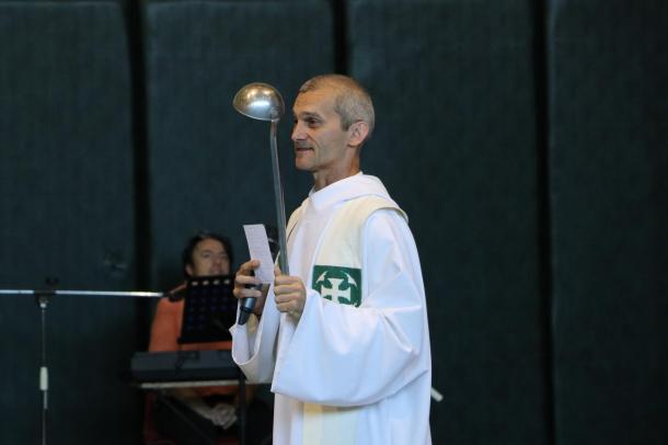 Szőke Gábor, római katolikus plébános egy szedőkanalat tart a kezében.