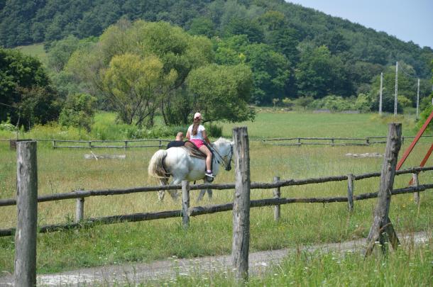 Egy lány kísérő felügyeletével lovagol.