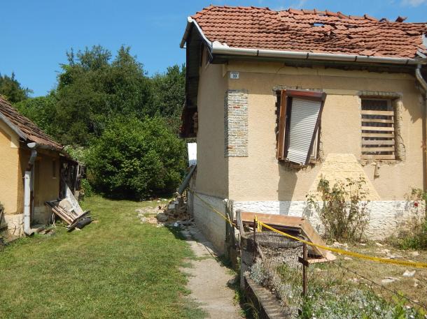 A robbanásban érintett borsodszentgyörgyi családi ház udvara. Leomlott téglák, bedeszkázott ablak.
