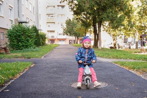 Egy kislány örömmel motorozik az új szakaszon a Bolyki főút 59-65. szám előtt.
