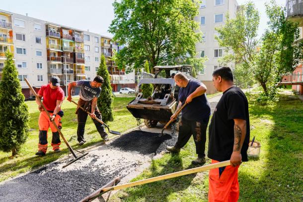 A szakemberek járdát aszfaltoznak a Bolyki főúti kocka házak között.