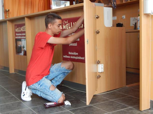 A diákmunka program egyik résztvevője takarítja az ajtót.