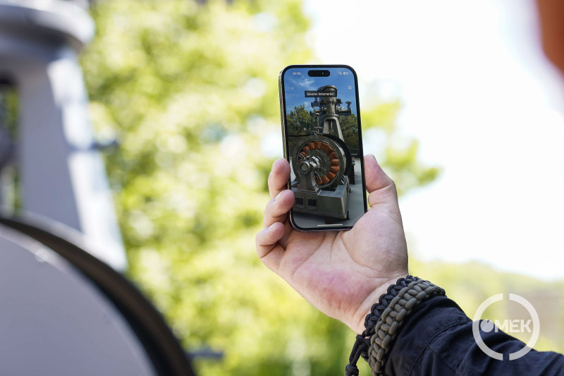 A telefonon keresztül látható ahogyan a gépszobor életre kel a kiterjesztett valóságban.