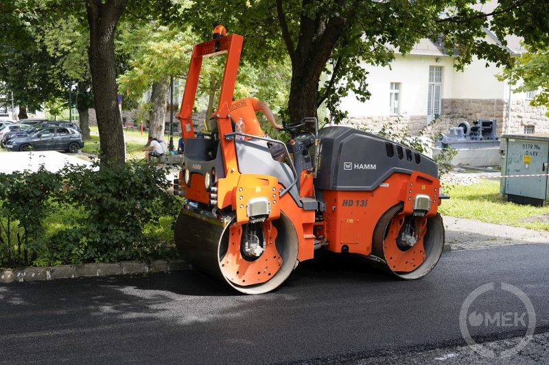 Az egyik szakember hengereli az új aszfaltréteget.