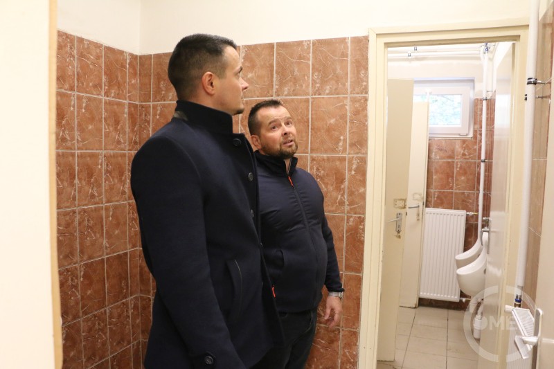 Janiczak Dávid polgármester és Tóth-Pintér Krisztián projektmenedzser szemrevételezik a felújított mellékhelyiséget.