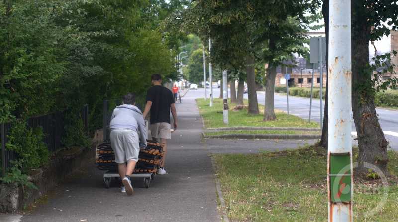 A múzeumból az Olvasóba viszik a szabadtéri székeket a diákmunkások.