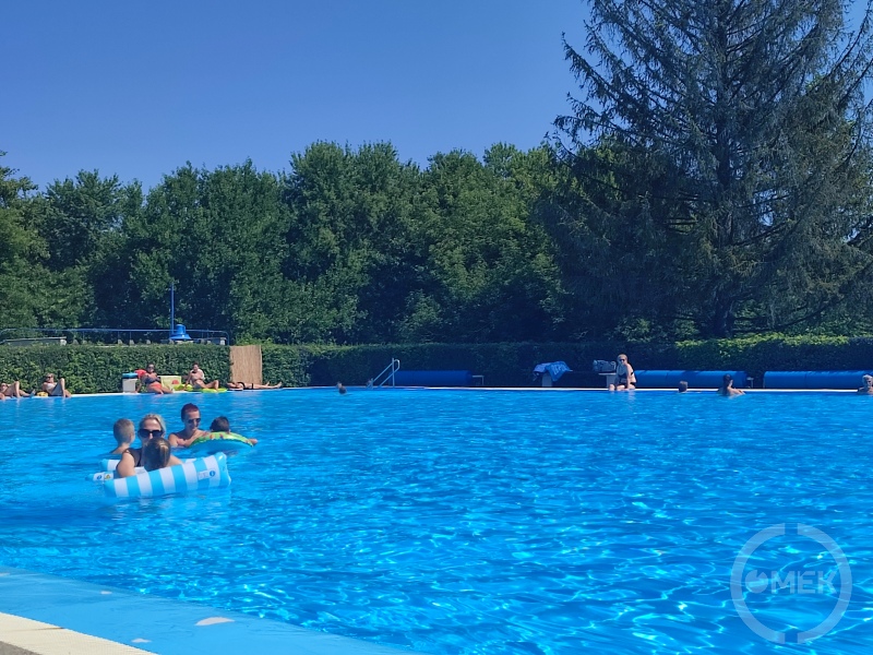 Gyerekükkel játszó szülők a medencében.