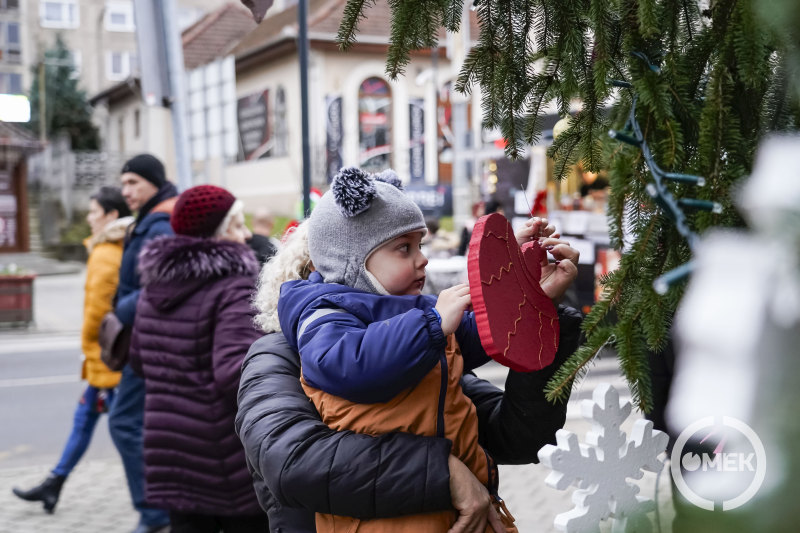 Egy kisfiú díszíti a karácsonyfát.