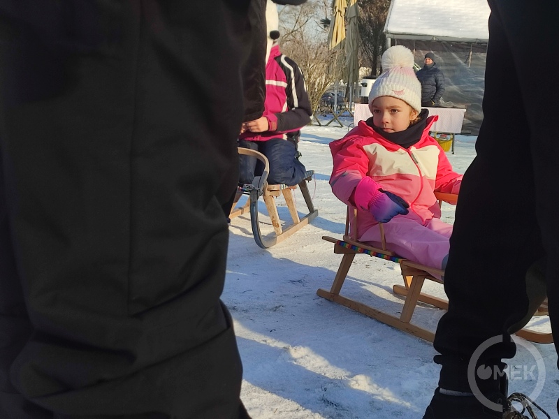 Egy kislány ül a szánkón.