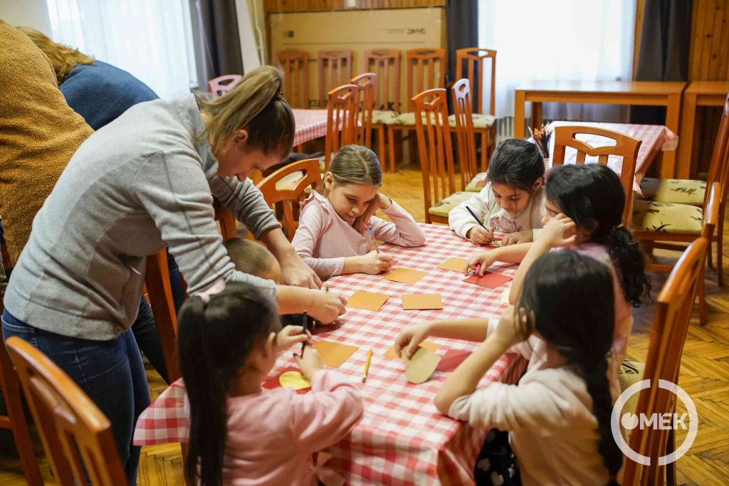 Az óvodapedagógus segít a gyerekeknek.