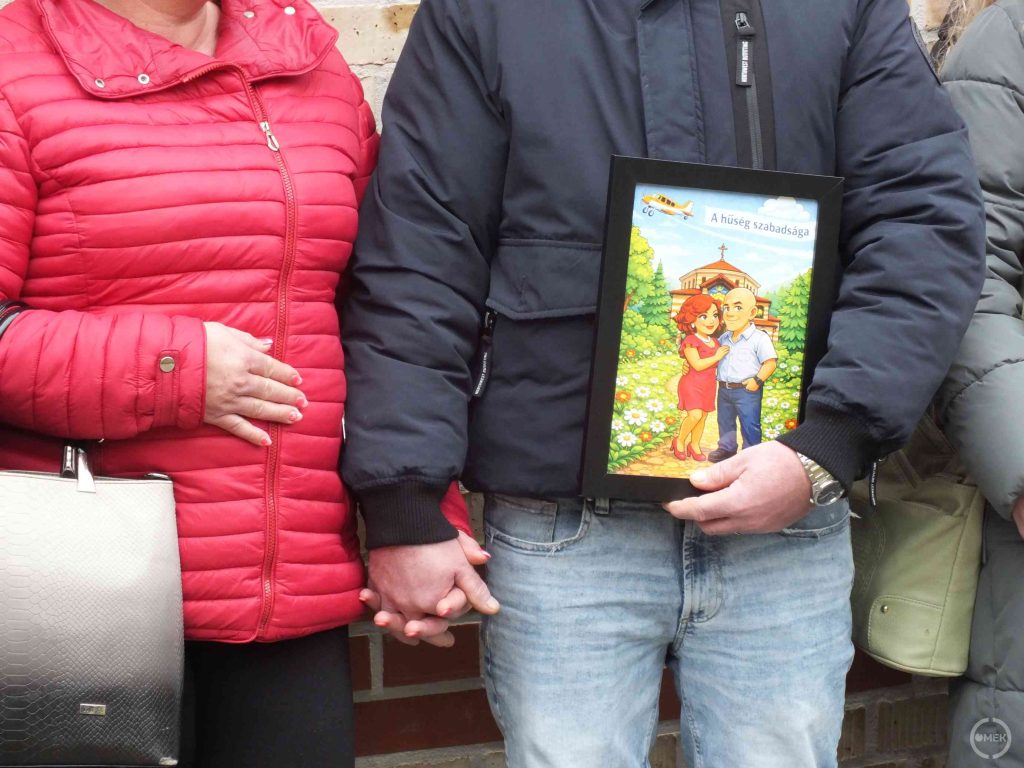 Egy házaspár egymás kezét fogva, a róluk szóló kis személyes ajándékkal.