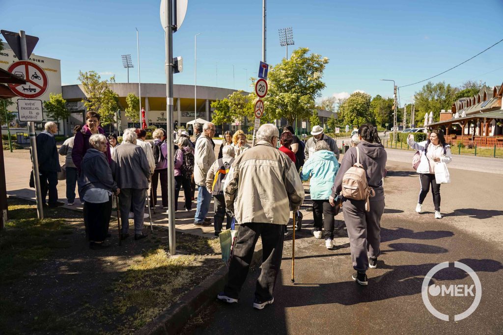 A buszról leszállva gyülekeznek az idősek.