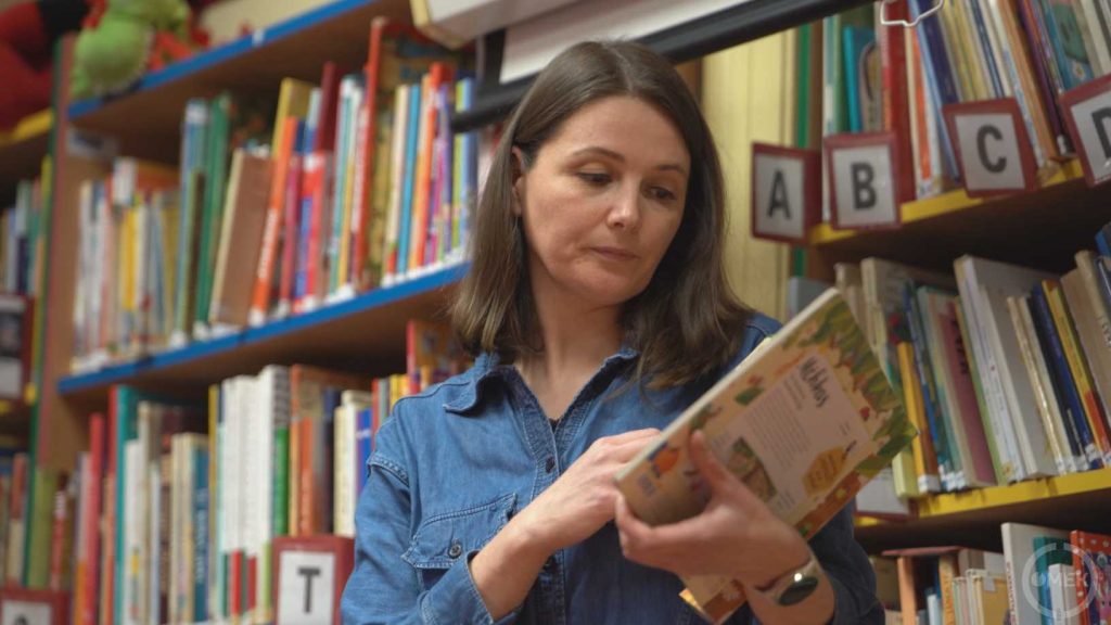 Kovács Adrienn, gyermekkönyvtáros egy könyvet mutat be a gyermekeknek.