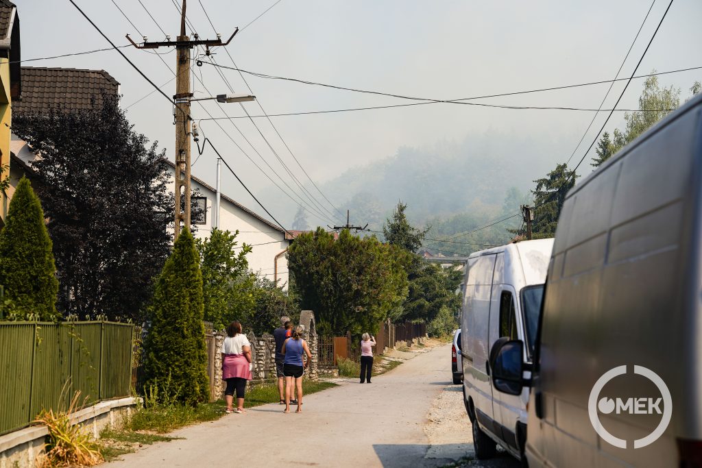 A lakók az utcáról szemlélik a füstfelhőt.