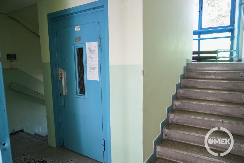 Egy lépcsőházi lift és a lépcsők.