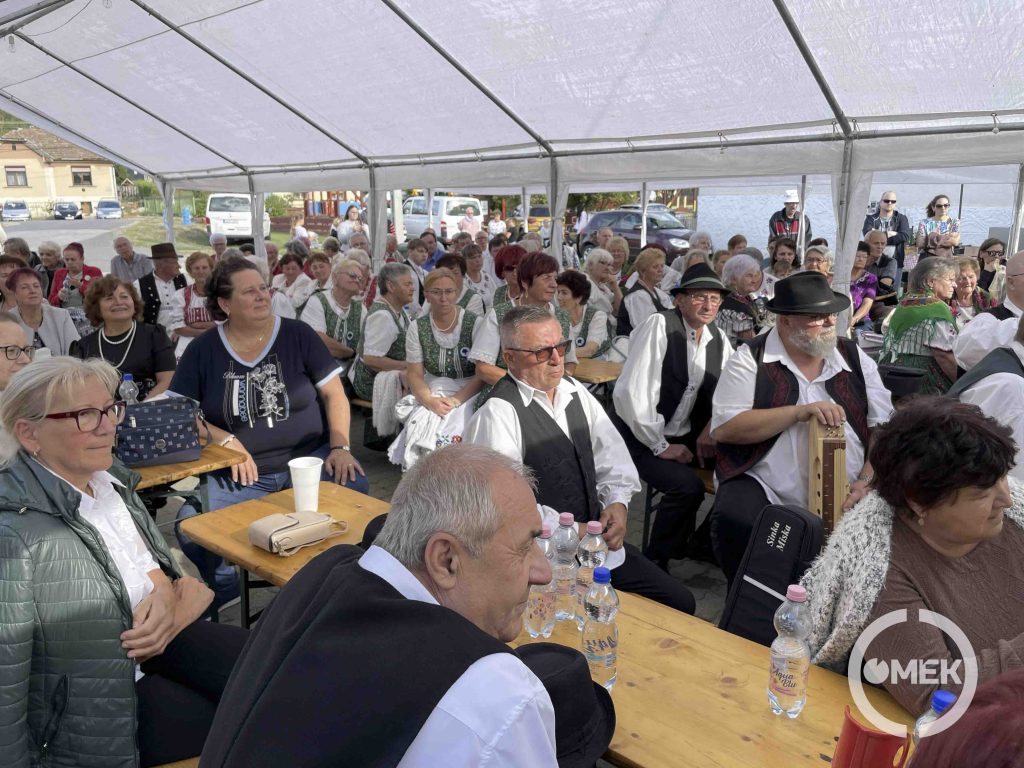 A hallgatóság ül a sátor alatt, a padokon.
