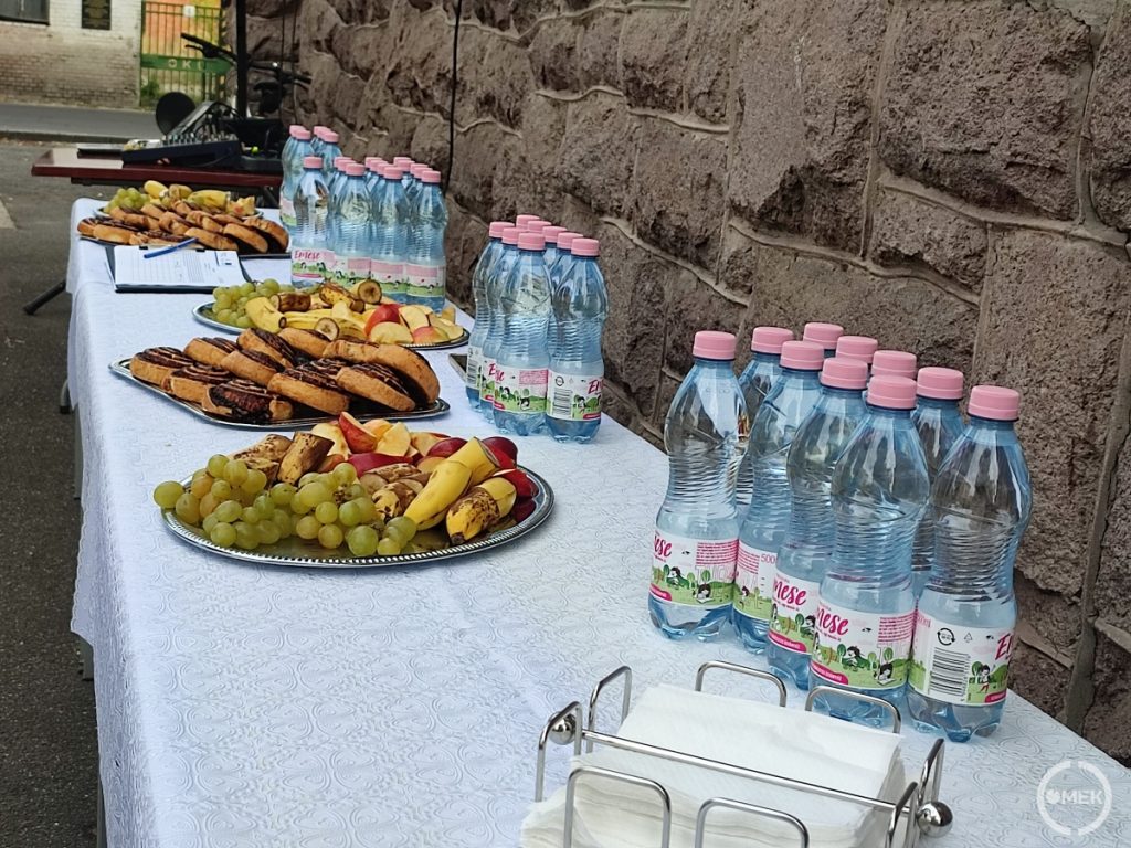 Kakaós csiga, víz és gyümölcsök az asztalon.