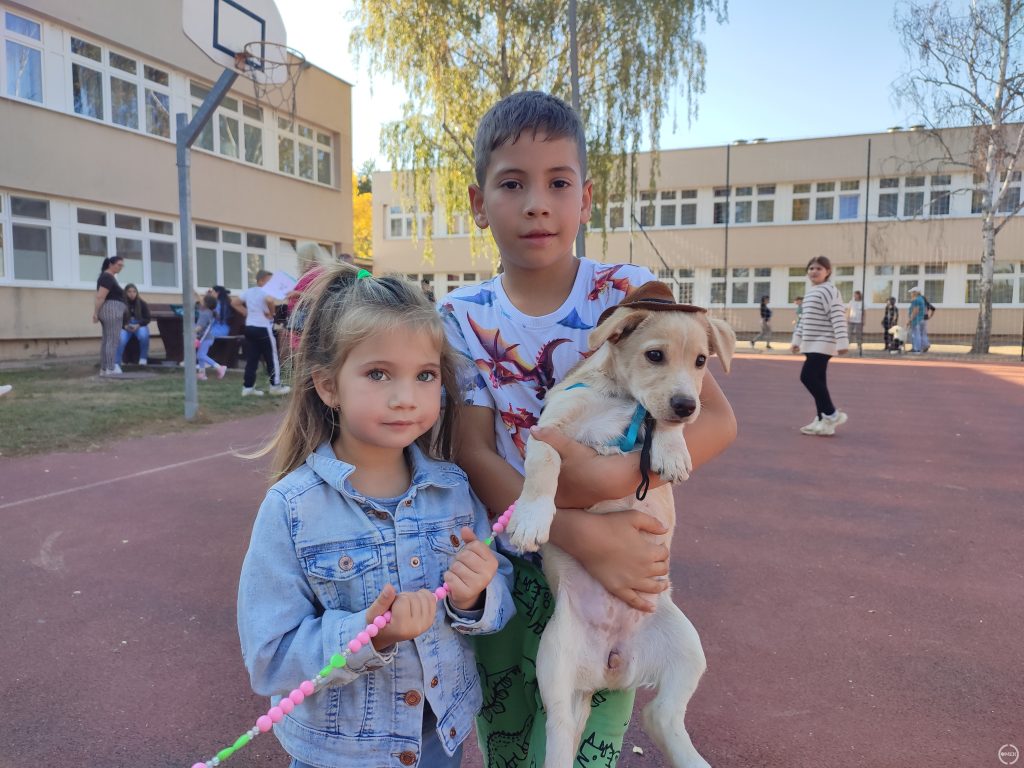 A gyerekek egy kiskutyát tartanak a kezükben.